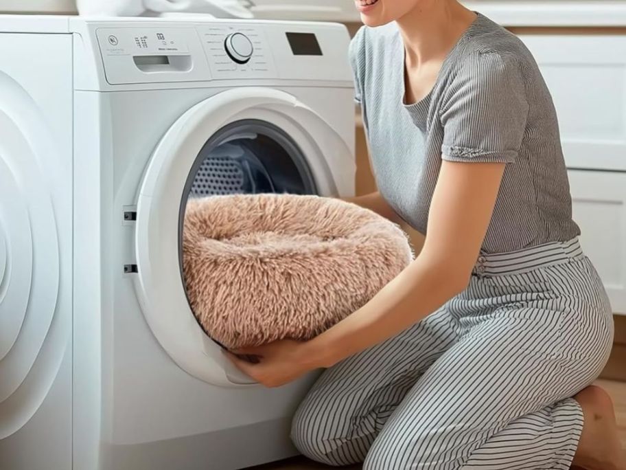 Woman putting a donut dog bed in a washing machine